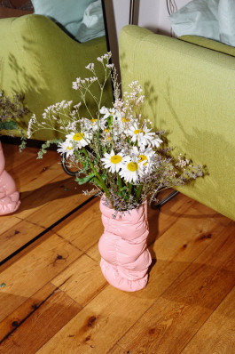 A pink vase with flowers standing on the floor Logo Progressive Present