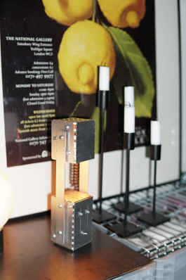 a silver metal lamp standing on a box Logo Progressive Present
