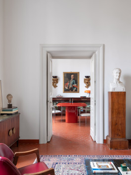 a red table standing in a room with various other items Logo Progressive Present