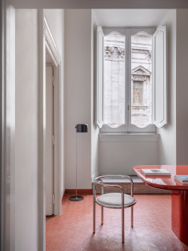 a red table standing in a room with various other items Logo Progressive Present