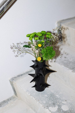 A black vase standing on concrete stairs Logo Progressive Present