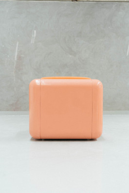 a rose chair standing on a neutral floor in front of a grey background Logo Progressive Present