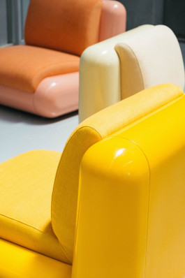 A yellow, a white and a orange-pink chair standing together Logo Progressive Present