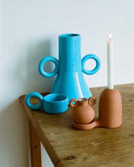 a blue vase and brown candle holder standin on a wooden table Logo Progressive Present