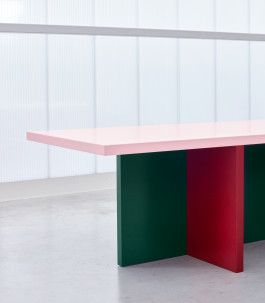 Tri-colored table standing in front of a plexiglass wall Logo Progressive Present