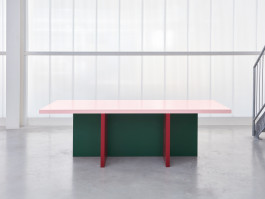 Tri-colored table standing in front of a plexiglass wall Logo Progressive Present