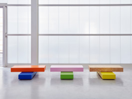 Wodden coffetables in various colors standing in front of a plexiglas wall Logo Progressive Present