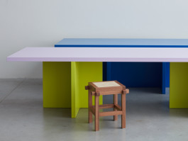 Two various colored tables standing next to each other on a grey floor Logo Progressive Present