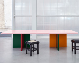 Tri-colored table standing in front of a plexiglass wall Logo Progressive Present