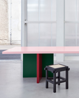 Tri-colored table standing in front of a plexiglass wall Logo Progressive Present