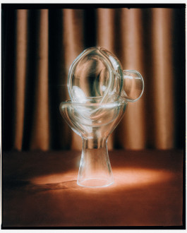 Photo of a glass vase standing in front of a brown curtain. Logo Progressive Present