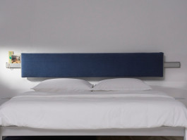 Modern bed with a minimalist blue upholstered headboard and white bedding – contemporary bedroom design. Logo Progressive Present