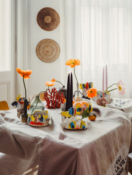 Artistic table setting with handmade ceramic sculptures, colorful flowers, and creative home decor accents Logo Progressive Present