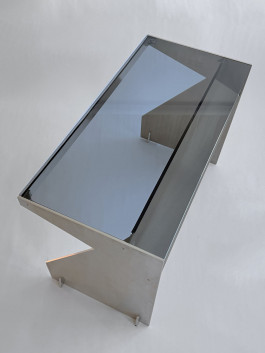 Minimalist desk with brushed metal frame and smoked glass top in modern lighting Logo Progressive Present