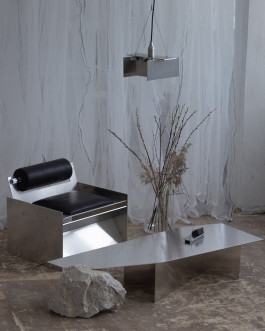 Contemporary interior with stainless steel lounge chair, angular metal coffee table, and geometric pendant light in a minimalist setting Logo Progressive Present