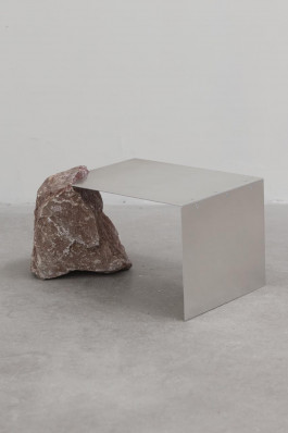 Minimalist side table with folded aluminum sheet supported by a raw natural stone on one side Logo Progressive Present