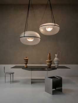 Modern interior with floating pendant lights, sculptural ceramic vases on a dark dining table, and minimalist stainless steel stool Logo Progressive Present