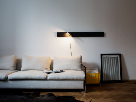 Horizontal wall lamp above a beige sofa in a minimalist living space Logo Progressive Present