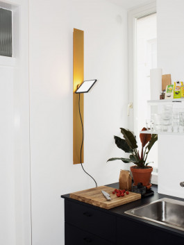 Slim yellow wall light in a minimalist white kitchen with black counter Logo Progressive Present
