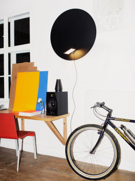 Workspace with circular black wall lamp and desk setup Logo Progressive Present