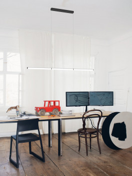 Minimal pendant light above a creative workspace with dual monitors and toy car Logo Progressive Present