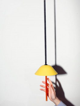 Yellow pendant light with orange rod, hand reaching up in strong shadow lighting Logo Progressive Present