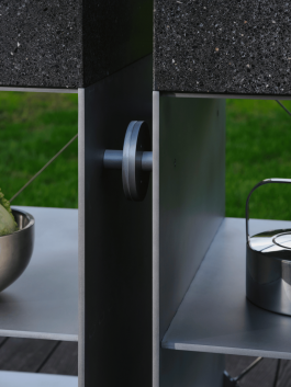 Close-up of a connection detail between two outdoor kitchen modules made of stone and stainless steel. Logo Progressive Present